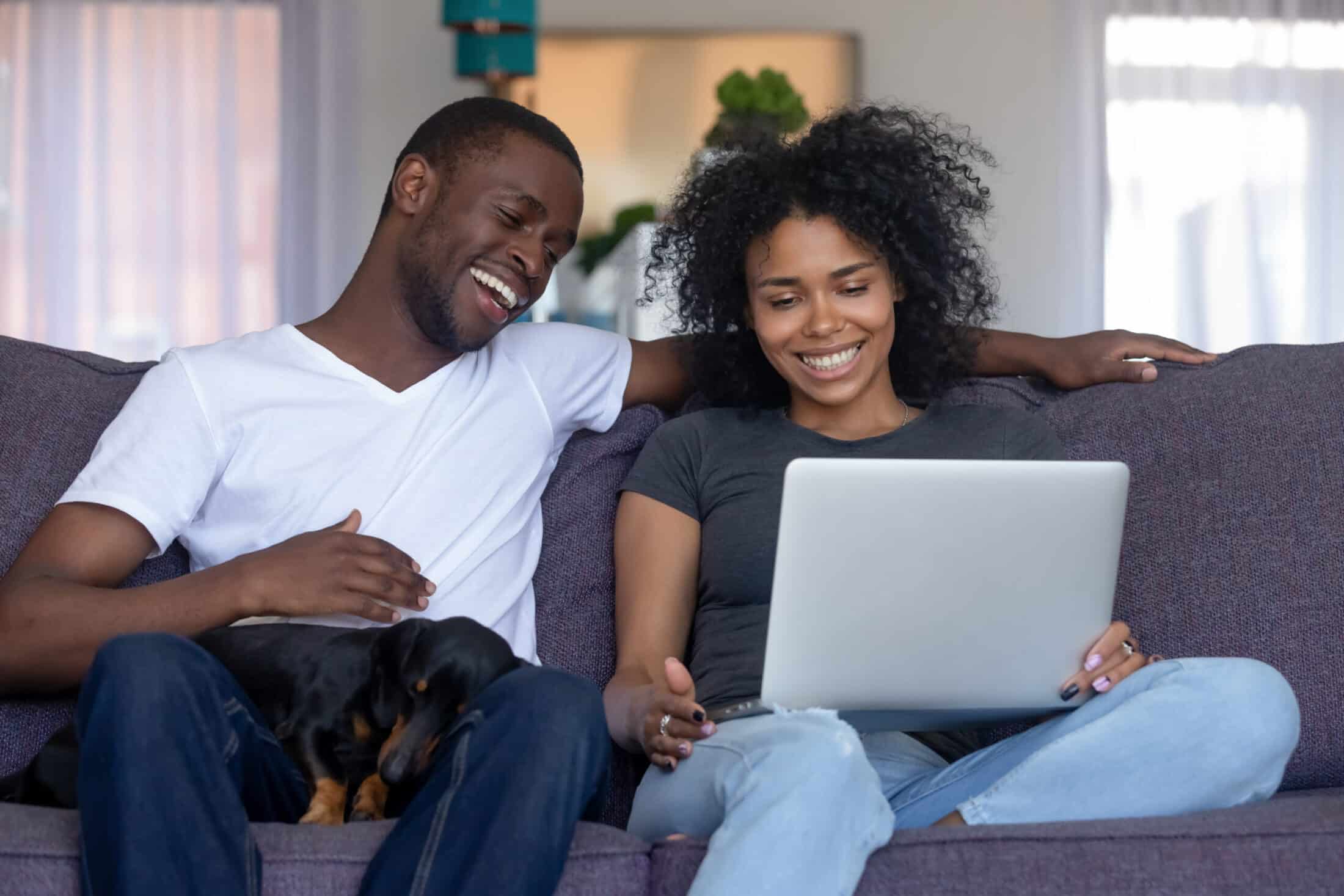 Smiling,African,American,Couple,Laughing,Using,Computer,Sitting,On,Couch