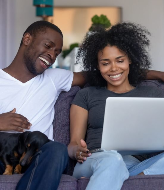 Smiling,African,American,Couple,Laughing,Using,Computer,Sitting,On,Couch